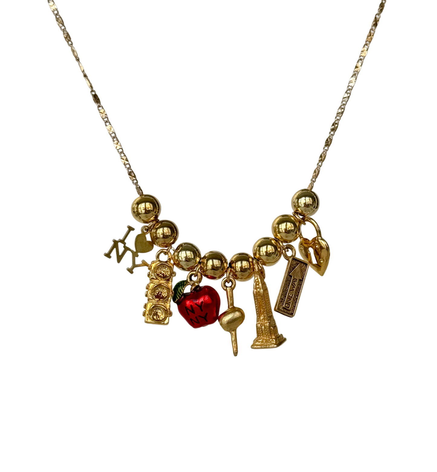 An 18K gold plated necklace featuring a variety of vintage and NYC-themed charms including a red apple, a traffic light, and the Empire State Building.